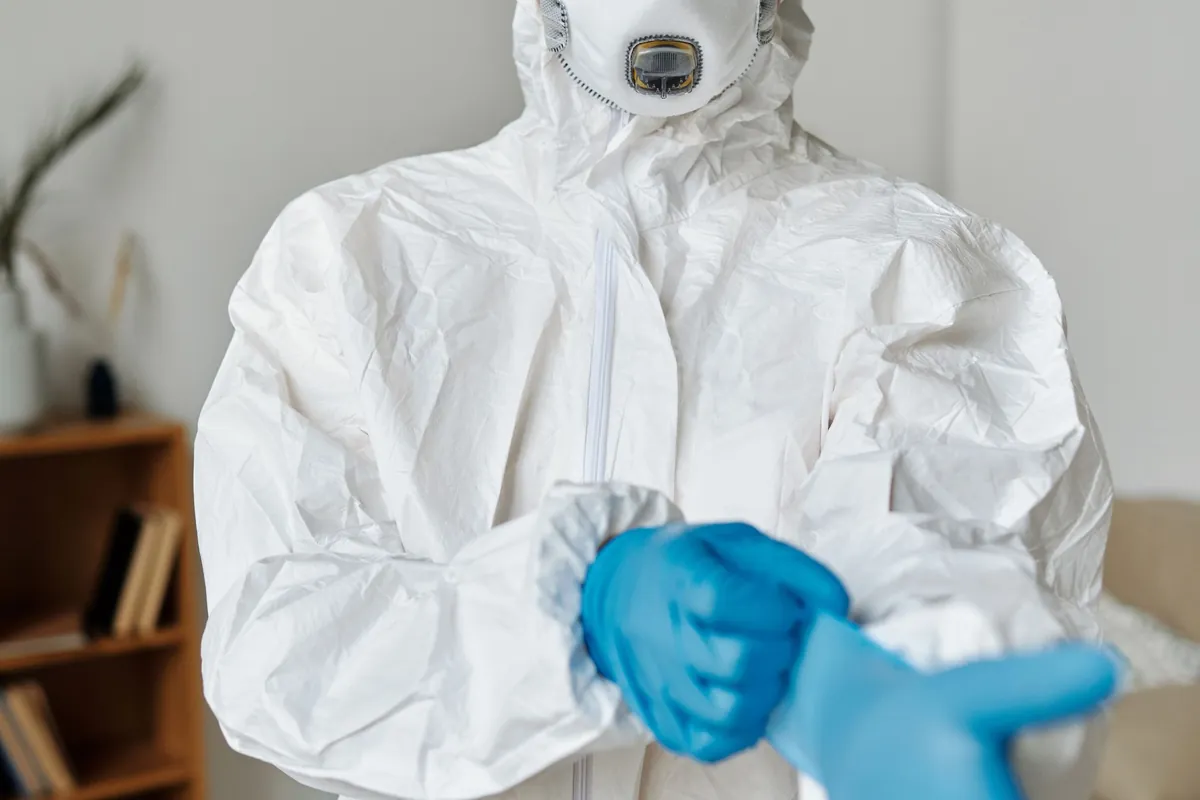 Asbestdeskundige trekt beschermende handschoenen aan