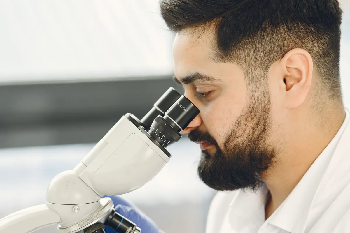 Laborant kijkt door een microscoop naar een materiaalstaal